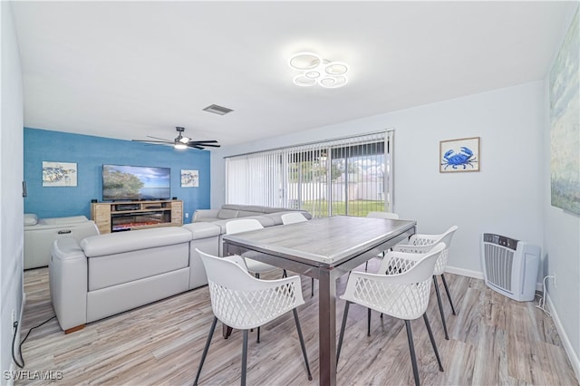 dining space with light hardwood / wood-style floors, a fireplace, and ceiling fan