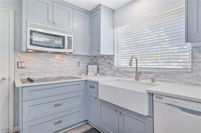 kitchen with dishwasher, light stone countertops, backsplash, and black electric stovetop