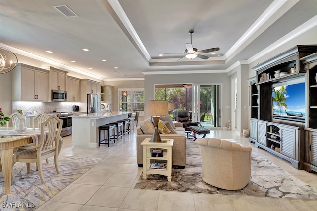 tiled living room featuring ceiling fan with notable chandelier, sink, a raised ceiling, and ornamental molding