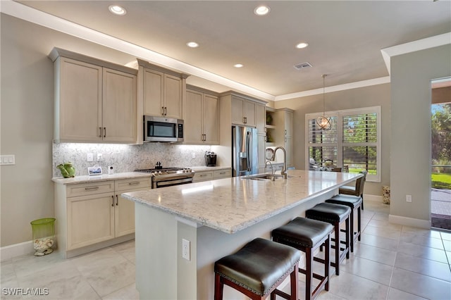 kitchen featuring a breakfast bar, light stone countertops, stainless steel appliances, a kitchen island with sink, and sink