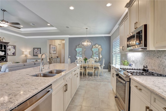 kitchen with tasteful backsplash, light stone countertops, stainless steel appliances, decorative light fixtures, and sink