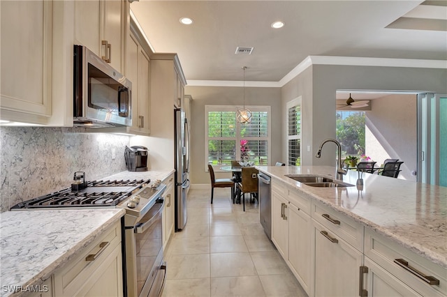 kitchen featuring hanging light fixtures, decorative backsplash, light stone counters, stainless steel appliances, and sink