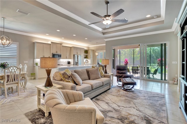 living room featuring light tile patterned flooring, ceiling fan with notable chandelier, crown molding, and a raised ceiling