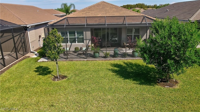 back of house featuring a yard, glass enclosure, and a patio