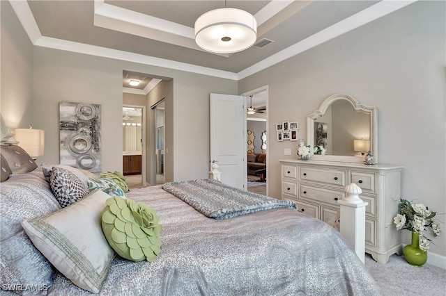 carpeted bedroom featuring crown molding, ensuite bathroom, and a raised ceiling