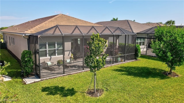 rear view of property with glass enclosure, a patio, and a lawn