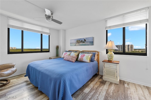 bedroom with multiple windows, ceiling fan, and hardwood / wood-style flooring