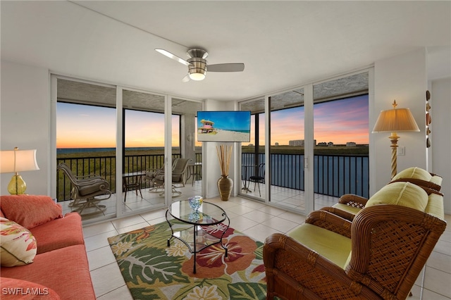 living room featuring ceiling fan, light tile patterned flooring, and a wall of windows