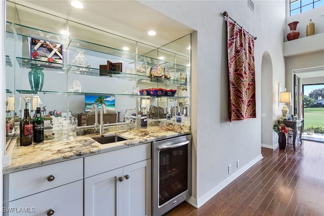 bar featuring white cabinets, wine cooler, sink, dark hardwood / wood-style floors, and light stone countertops