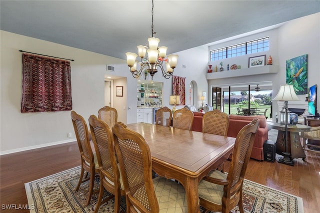 dining space featuring a high ceiling, an inviting chandelier, and dark hardwood / wood-style flooring