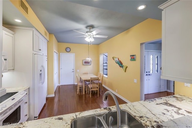 kitchen with light stone counters, white cabinets, sink, white appliances, and dark hardwood / wood-style flooring