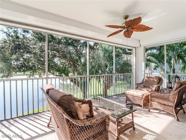 sunroom featuring ceiling fan, a water view, and a healthy amount of sunlight