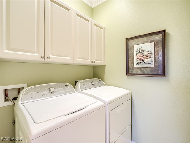 laundry room featuring crown molding, washing machine and clothes dryer, and cabinets