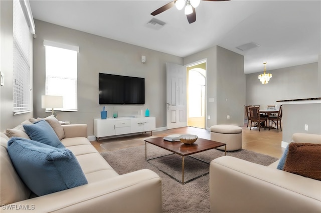 living room featuring ceiling fan with notable chandelier