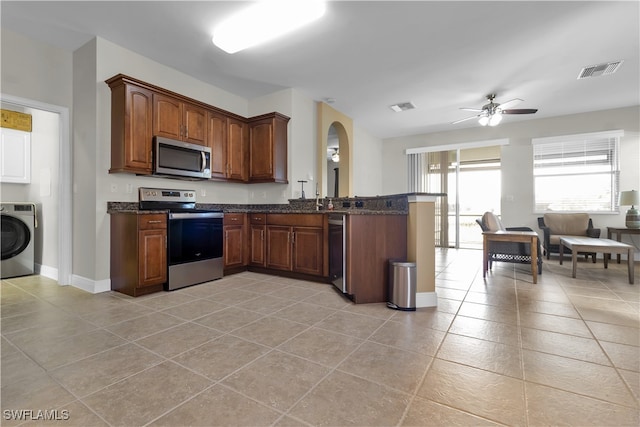 kitchen featuring washer / dryer, kitchen peninsula, appliances with stainless steel finishes, light tile patterned floors, and ceiling fan