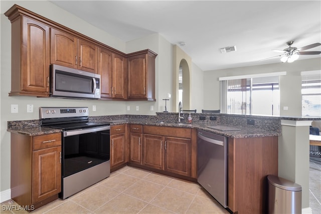 kitchen featuring appliances with stainless steel finishes, dark stone countertops, sink, and light tile patterned floors