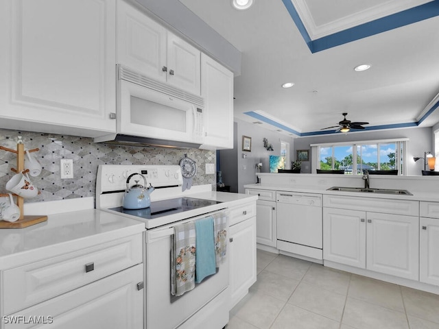 kitchen featuring a tray ceiling, sink, white cabinets, white appliances, and light tile patterned floors