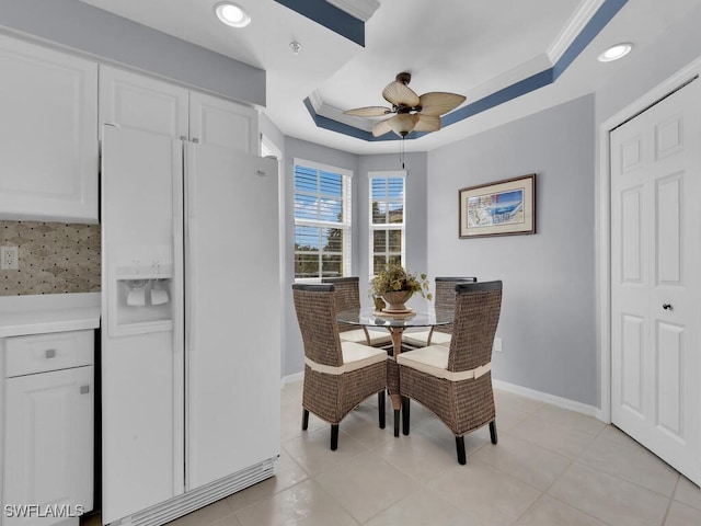 dining space featuring light tile patterned flooring, a tray ceiling, and ceiling fan