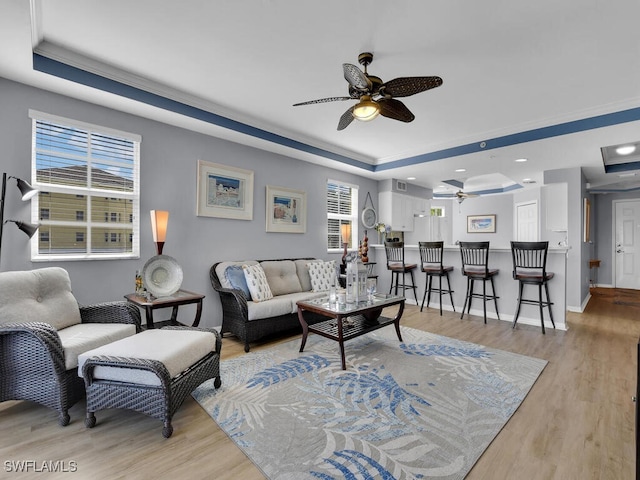 living room featuring ceiling fan, a raised ceiling, and light hardwood / wood-style floors