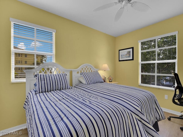 bedroom with multiple windows, ceiling fan, and hardwood / wood-style flooring