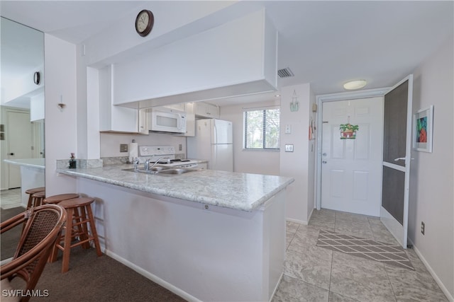 kitchen featuring white cabinets, kitchen peninsula, sink, light tile patterned floors, and white appliances