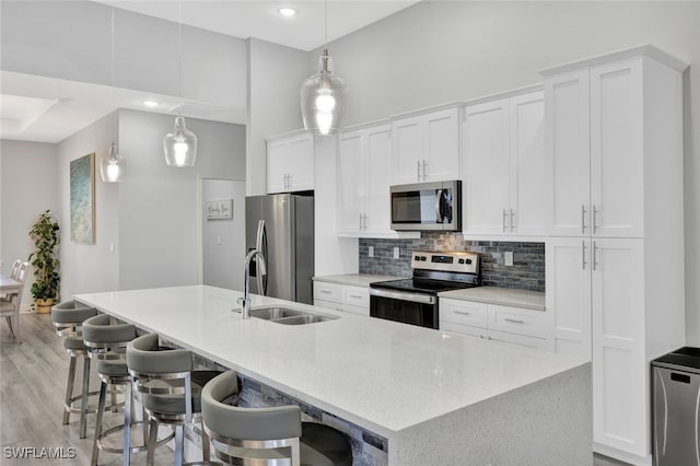 kitchen featuring a large island with sink, appliances with stainless steel finishes, and white cabinets