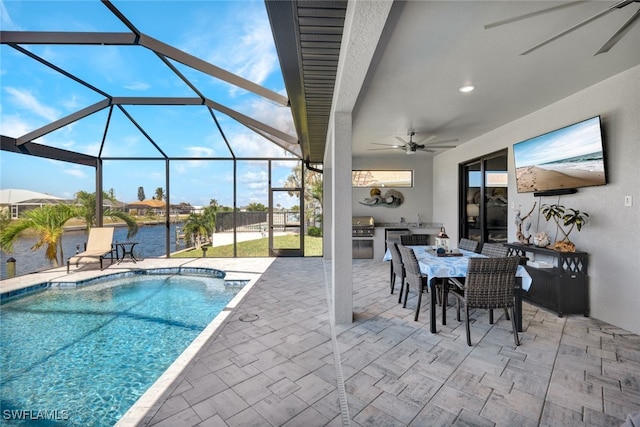 view of swimming pool featuring a patio area, a lanai, exterior kitchen, ceiling fan, and a water view