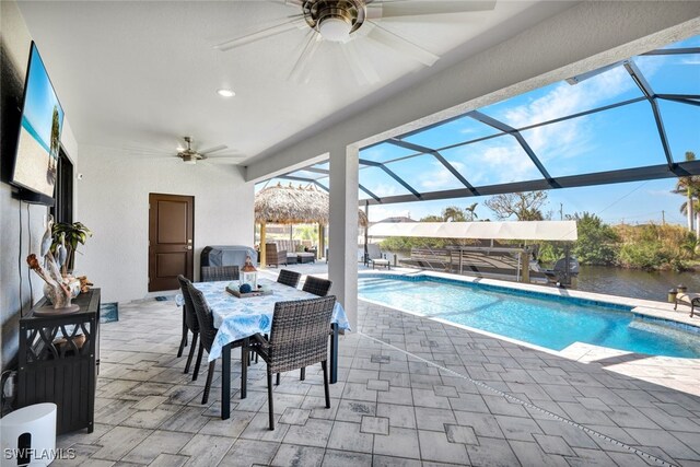 view of swimming pool with a patio, a lanai, a water view, and ceiling fan