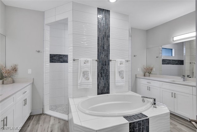 bathroom featuring vanity, hardwood / wood-style flooring, and plus walk in shower