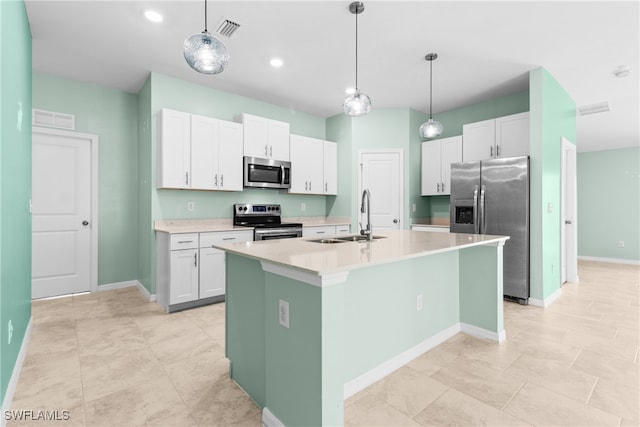 kitchen featuring a kitchen island with sink, pendant lighting, sink, white cabinets, and appliances with stainless steel finishes