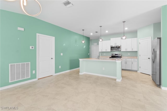 kitchen featuring an island with sink, sink, decorative light fixtures, white cabinetry, and appliances with stainless steel finishes