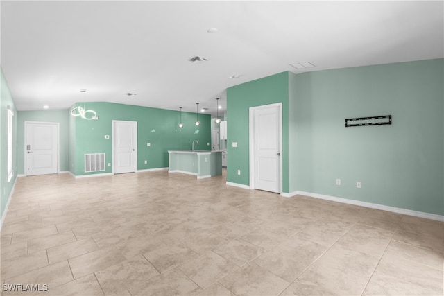 unfurnished living room with vaulted ceiling, sink, and an inviting chandelier