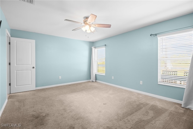 carpeted spare room featuring a healthy amount of sunlight and ceiling fan