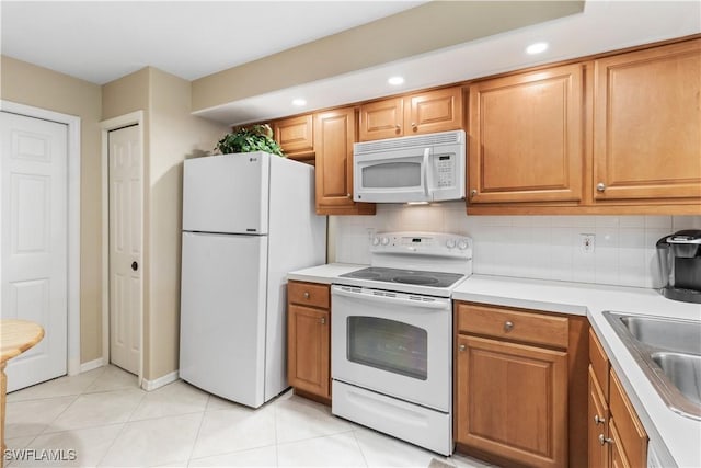 kitchen with sink, light tile patterned floors, backsplash, and white appliances