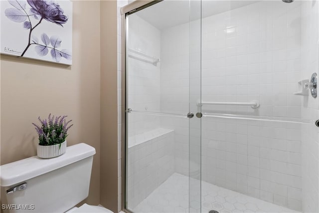 bathroom featuring toilet and a shower with shower door