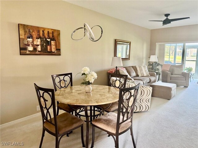 dining space with ceiling fan and light carpet