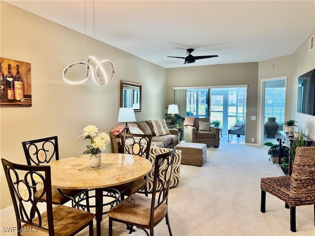 carpeted dining area with ceiling fan