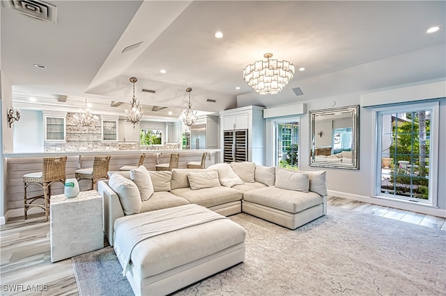 living room featuring a notable chandelier, a raised ceiling, and light hardwood / wood-style floors