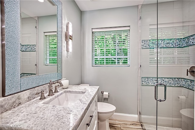 bathroom with an enclosed shower, plenty of natural light, vanity, and toilet