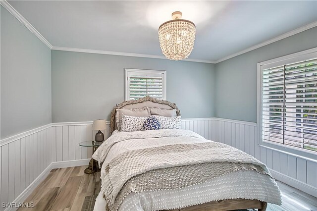 bedroom with crown molding, light hardwood / wood-style flooring, and a notable chandelier