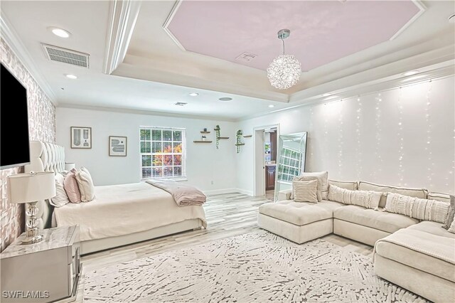 bedroom featuring light hardwood / wood-style flooring, a tray ceiling, a notable chandelier, and ornamental molding