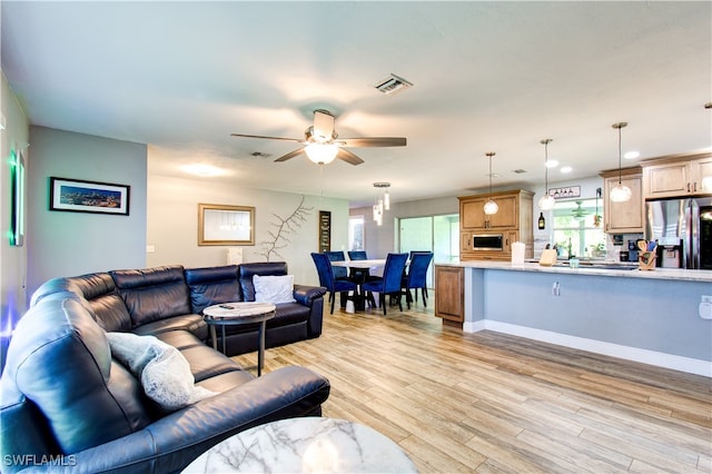 living room with light hardwood / wood-style floors and ceiling fan