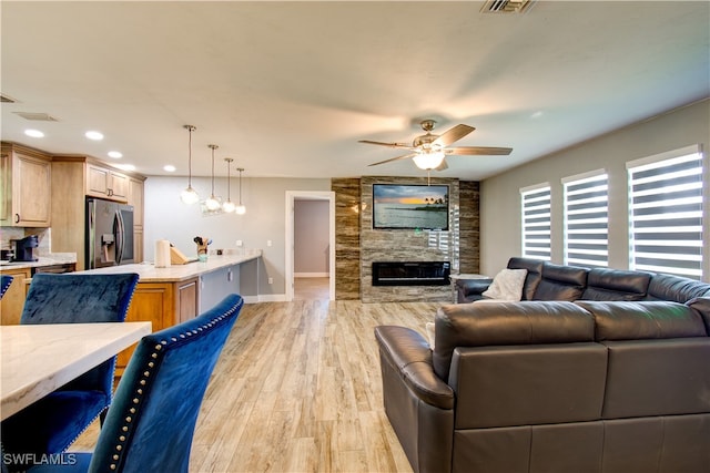 living room with ceiling fan, light wood-type flooring, and a fireplace