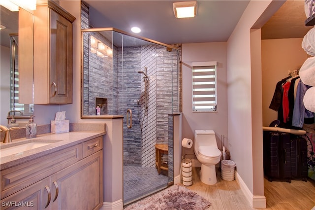 bathroom with vanity, wood-type flooring, a shower with shower door, and toilet