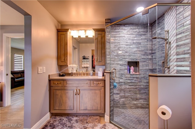 bathroom featuring a healthy amount of sunlight, hardwood / wood-style floors, walk in shower, and vanity