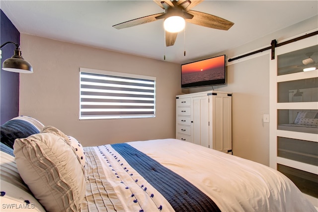 bedroom with ceiling fan and a barn door