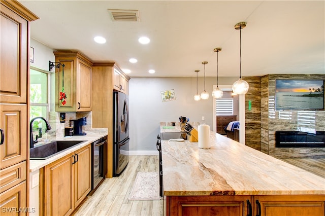 kitchen with light wood-type flooring, tasteful backsplash, range, sink, and stainless steel fridge