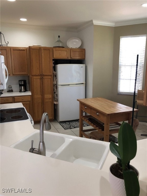 kitchen featuring sink, ornamental molding, and white appliances