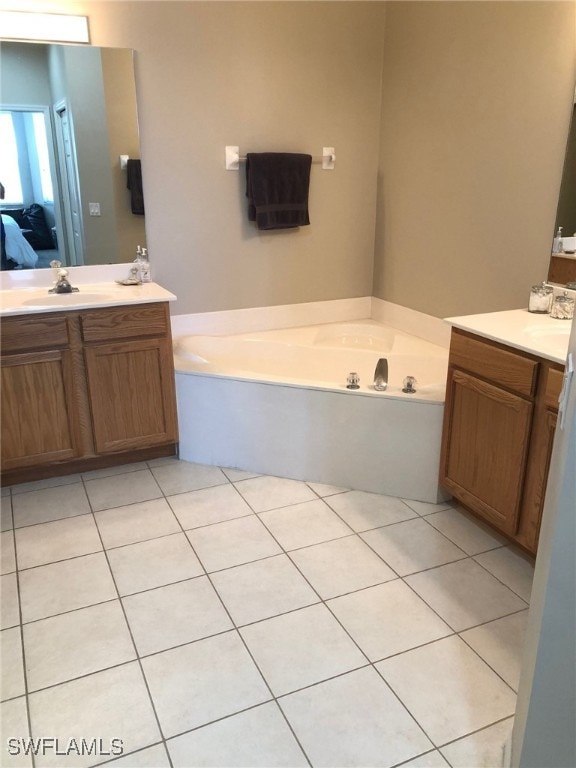 bathroom featuring tile patterned flooring, a bath, and vanity