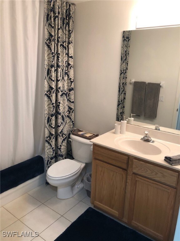 bathroom featuring a shower with curtain, vanity, toilet, and tile patterned floors